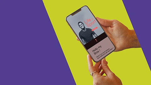 Mains tenant un téléphone affichant le hero banner d'un bel homme affichant un beau sourir